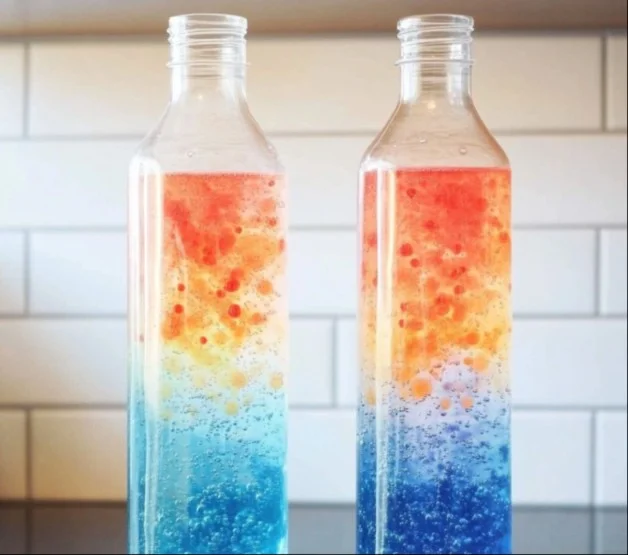 A colorful DIY lava lamp with vibrant wax blobs rising and falling in a glass bottle.