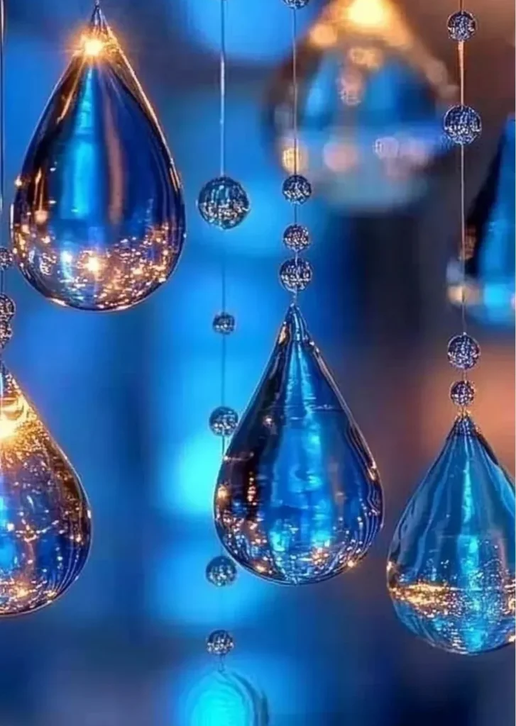 Colorful blue crayon suncatchers hanging in a window, catching sunlight.