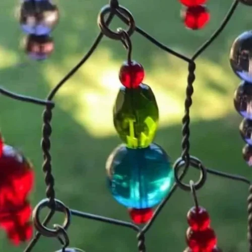 Colorful handmade sun catcher made from wire mesh reflecting sunlight.